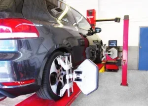 Car undergoing a wheel alignment at an automotive service station.